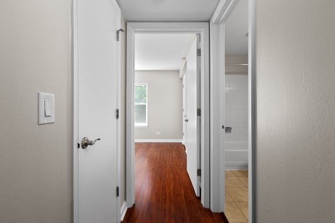 a bedroom with a door open to a hallway with a hard wood floor