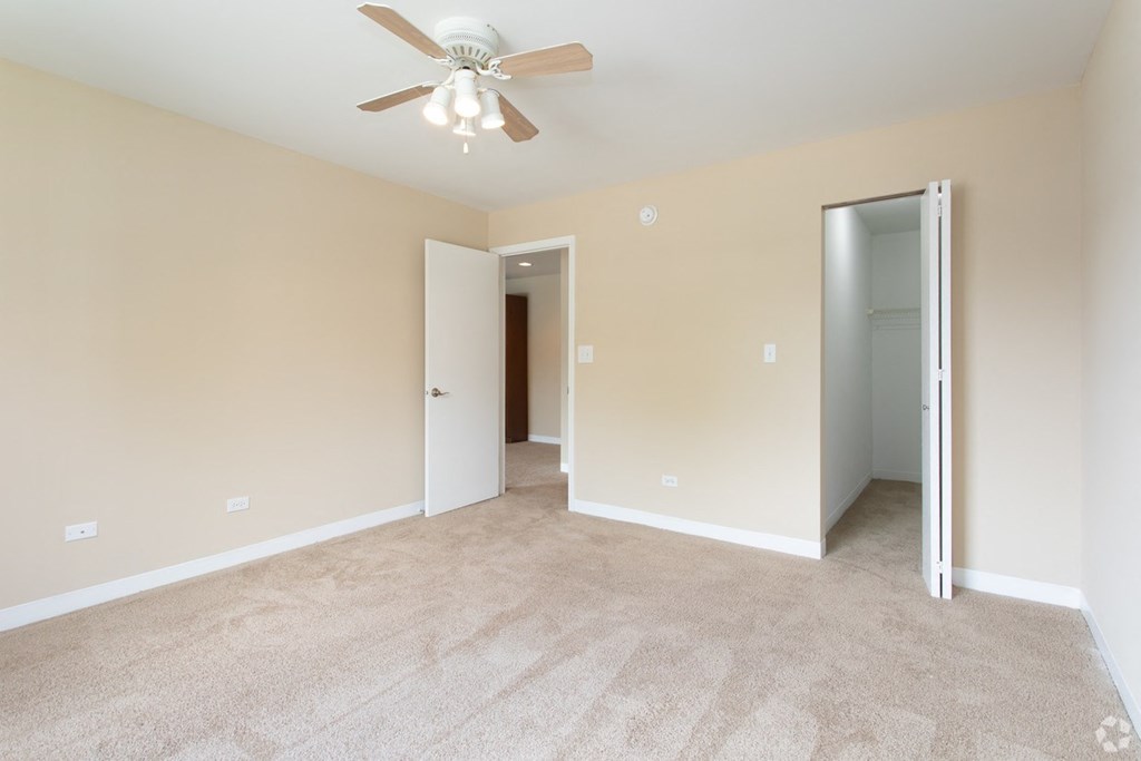 an empty living room with a ceiling fan and a door to a closet