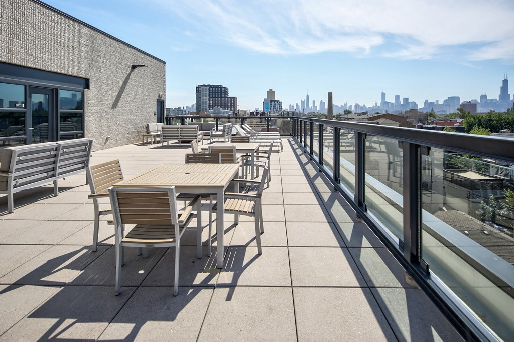 a roof deck with tables and chairs and a view of the city
