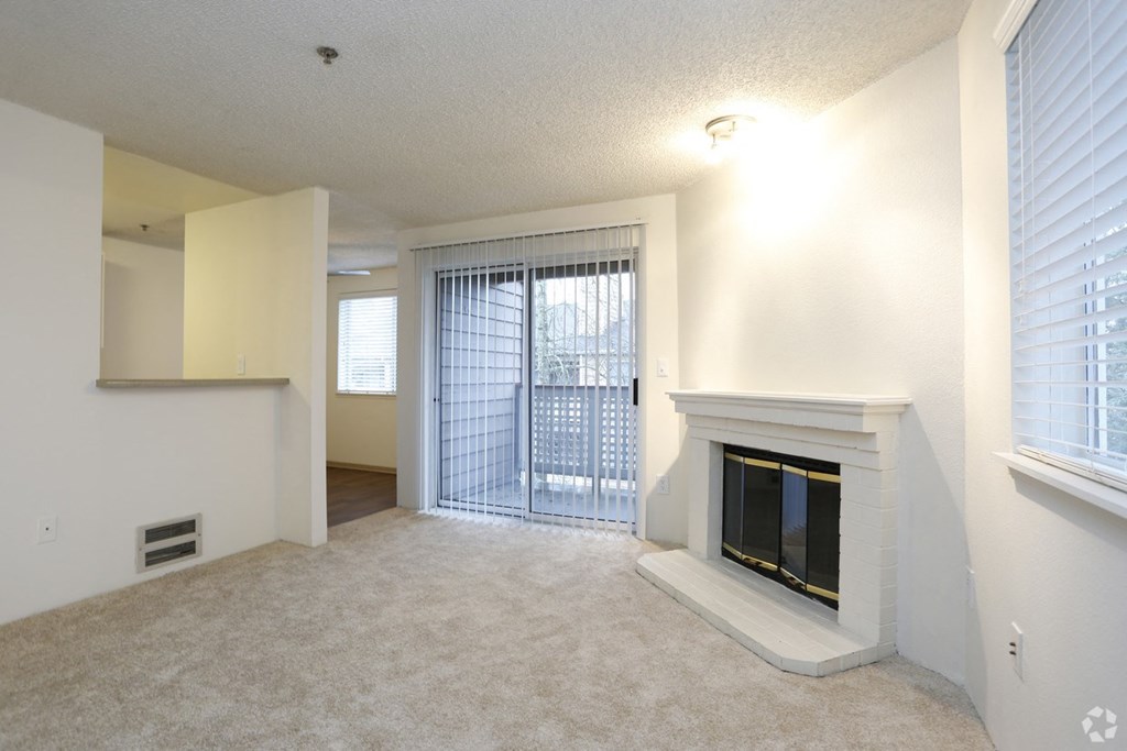 an empty living room with a fireplace and a door to a balcony