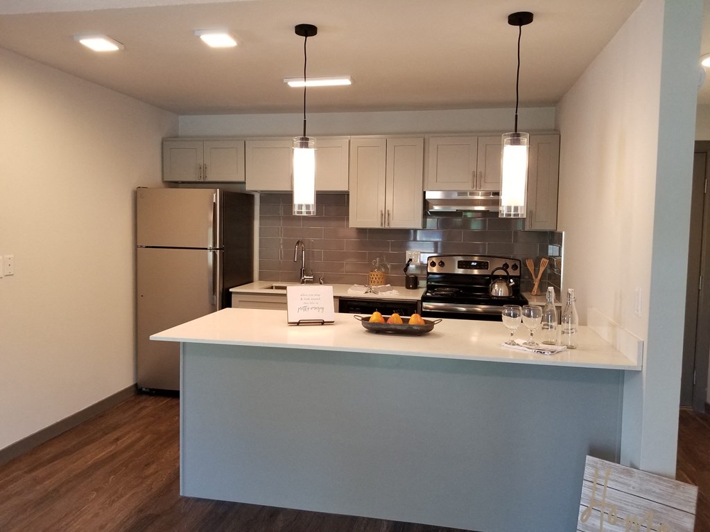 a kitchen with a white counter top and a stainless steel refrigerator