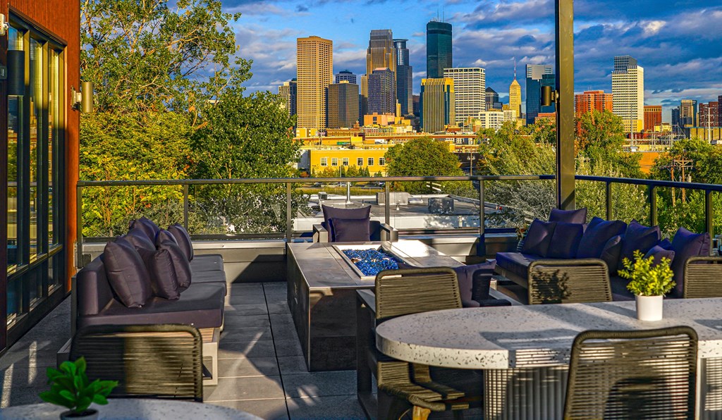 a rooftop patio with tables and chairs and a view of the city