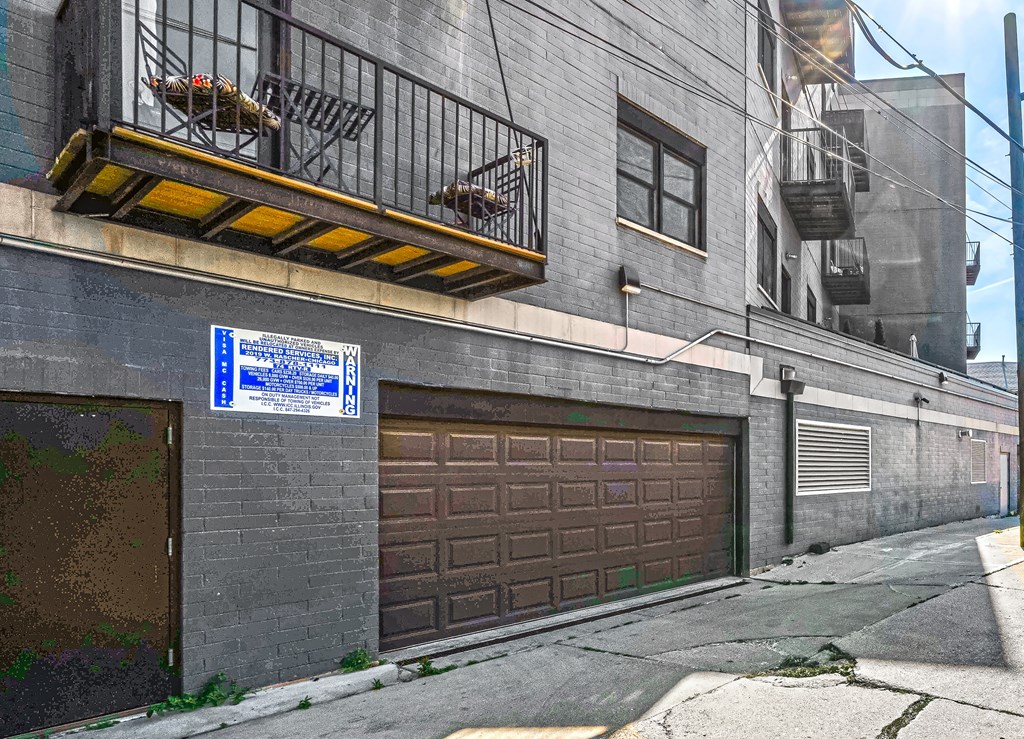 A blue and white sign is on a pole in front of a closed brown garage door.