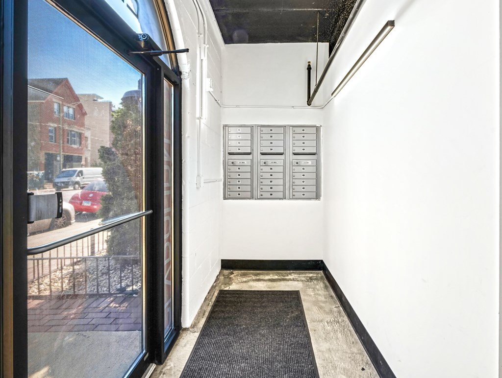 A view of a balcony with a black railing and a red car in the background.