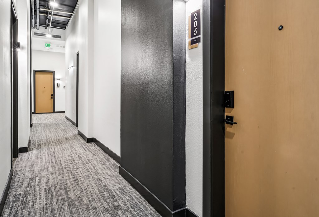 A hallway with a door on the right and a sign on the wall.