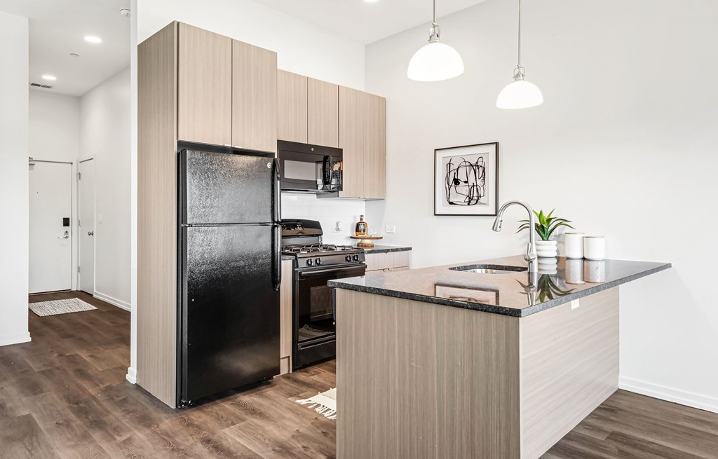 A modern kitchen with a black fridge and wooden cabinets.