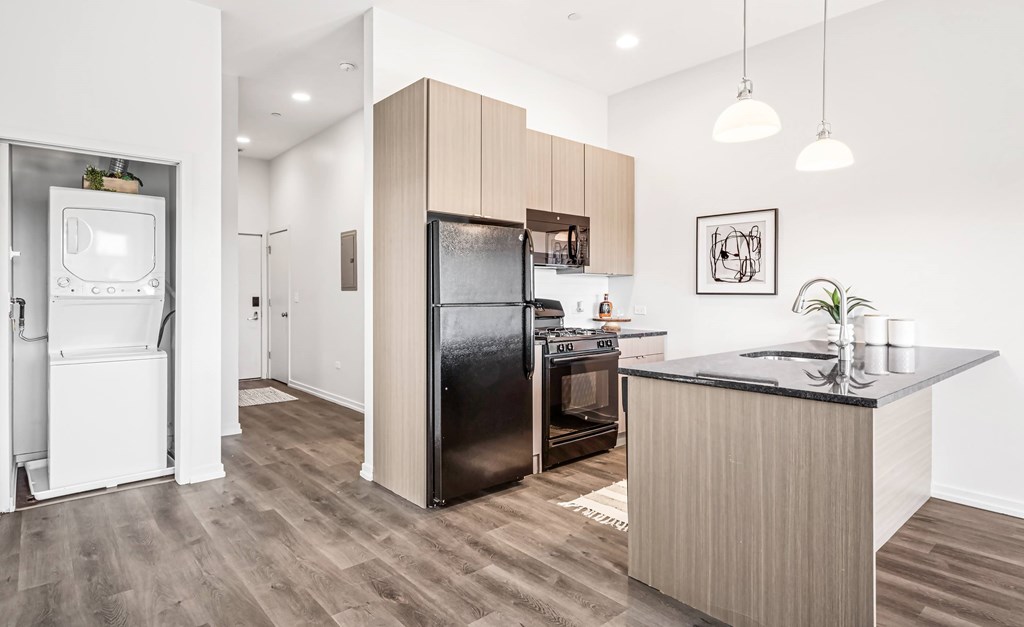 A modern kitchen with a black fridge and wooden cabinets.