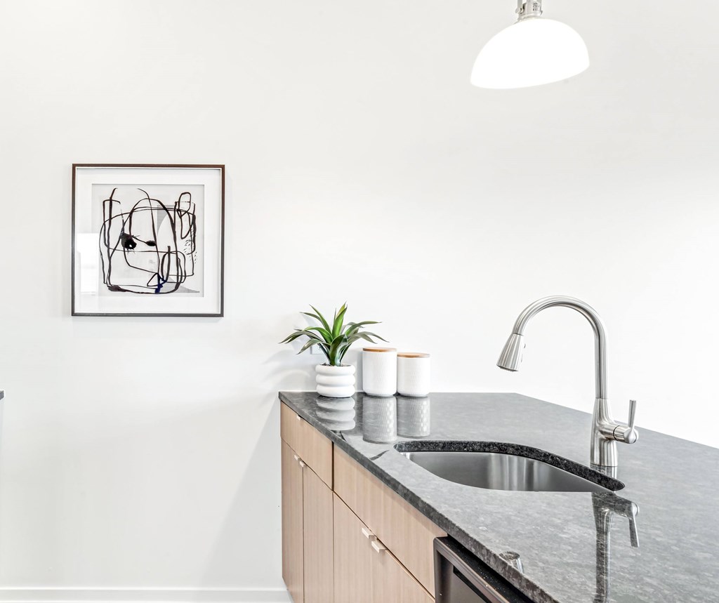 A modern kitchen with a sink and a framed abstract art piece on the wall.