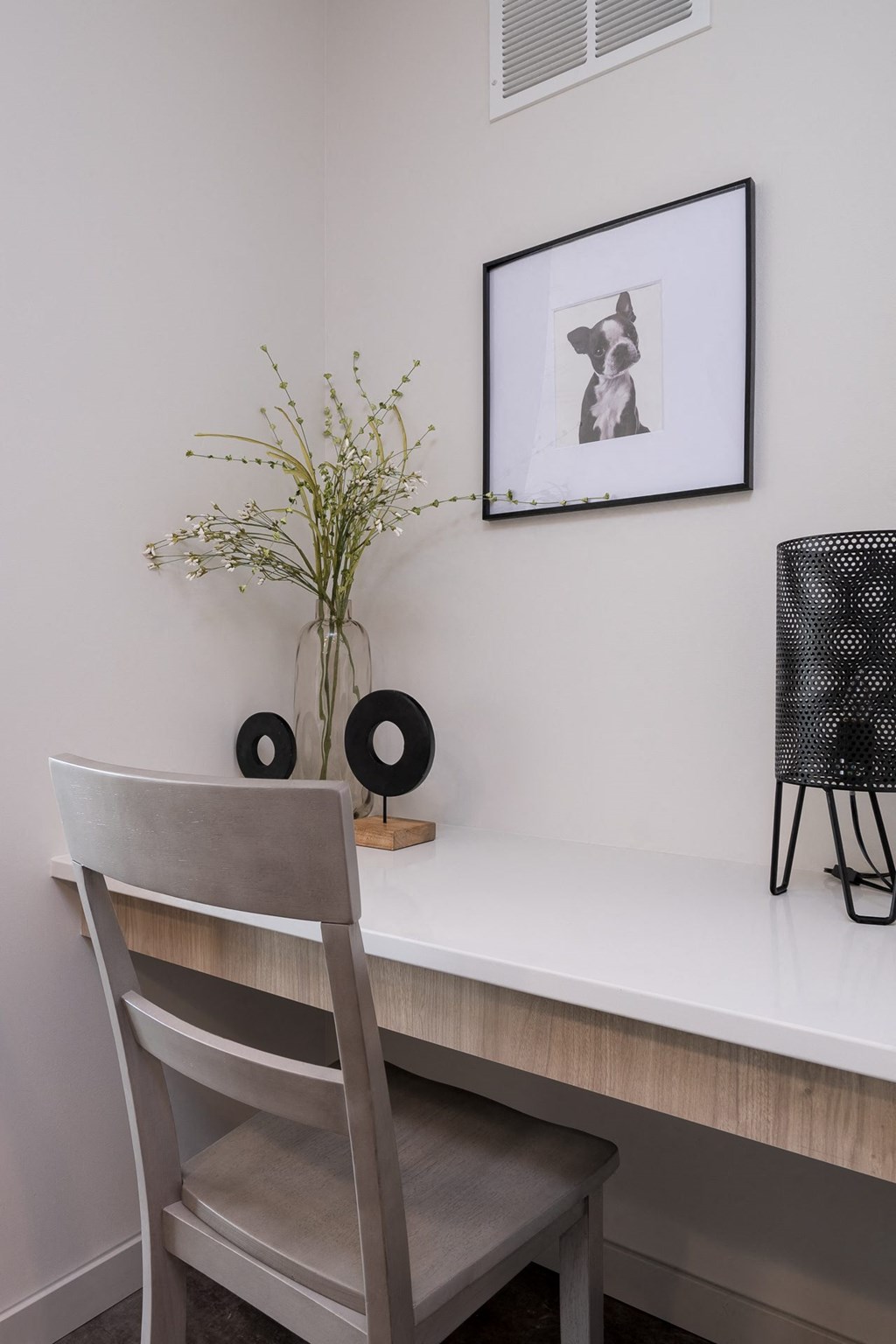 a desk with a chair and a vase with flowers on it