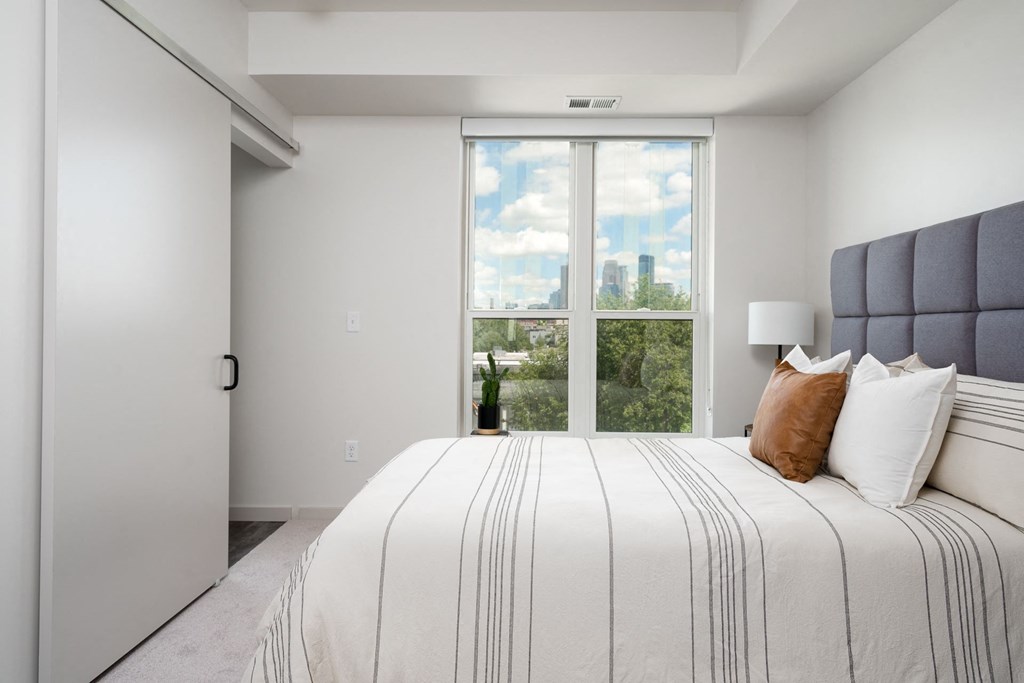 a white bedroom with a large bed and a window