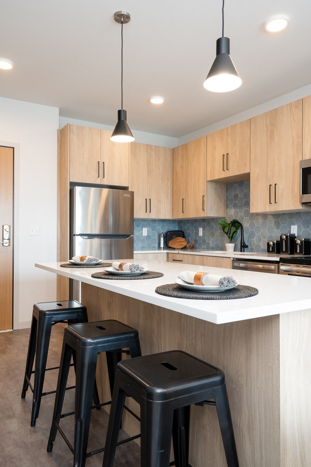 a kitchen with a white counter top and three stools