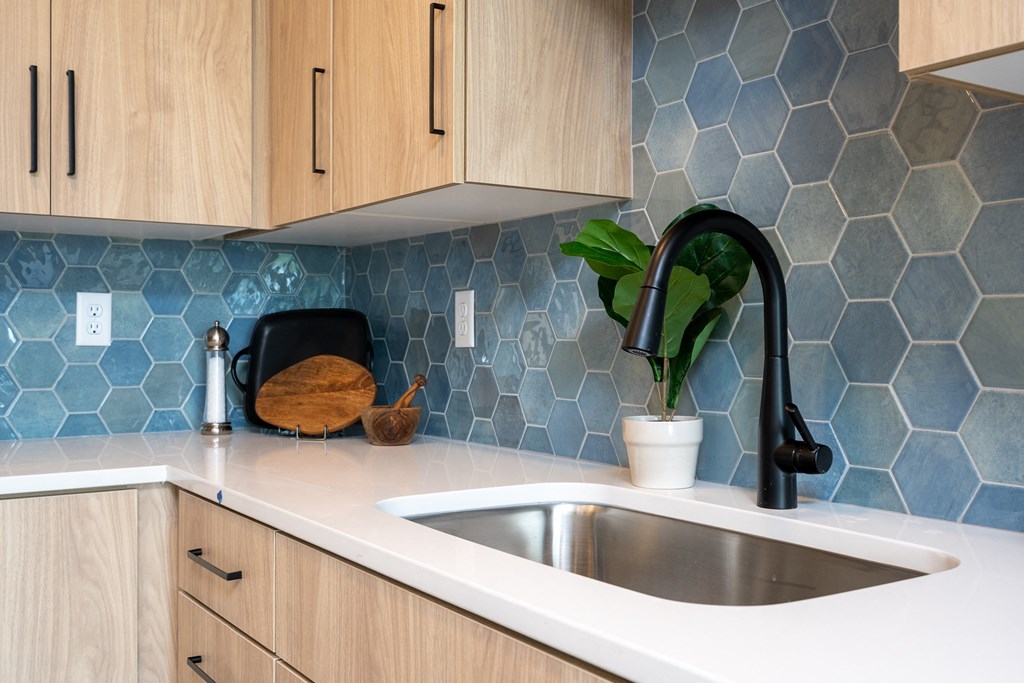 a kitchen with blue tiles on the wall and a sink
