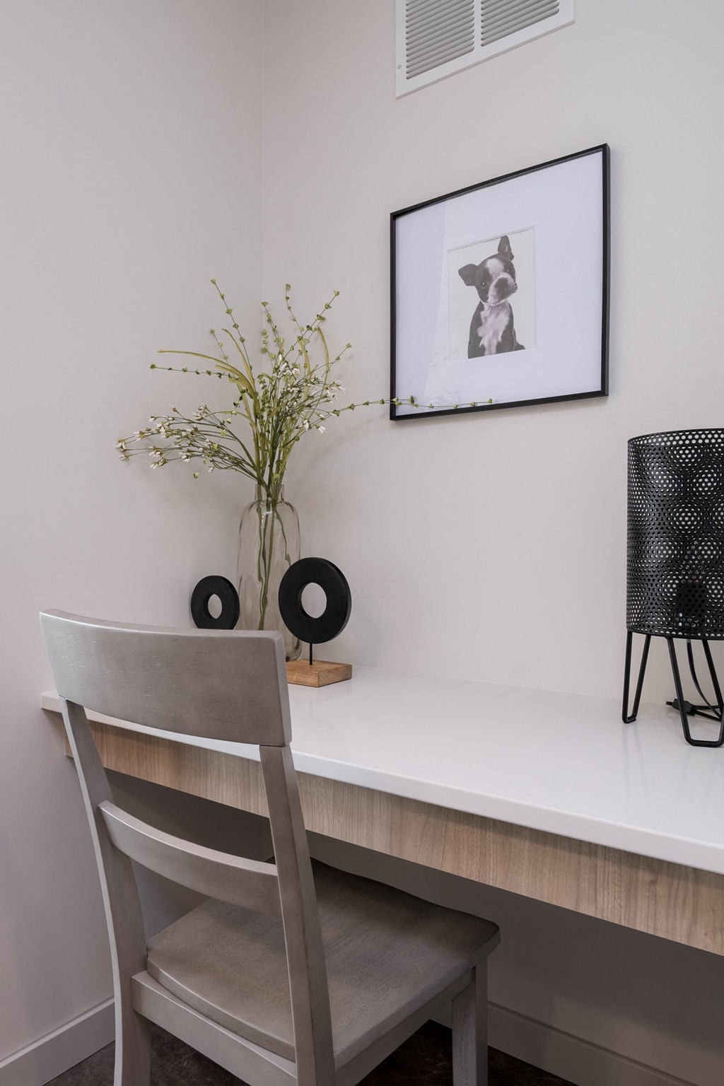 a desk with a chair and a vase with flowers on it