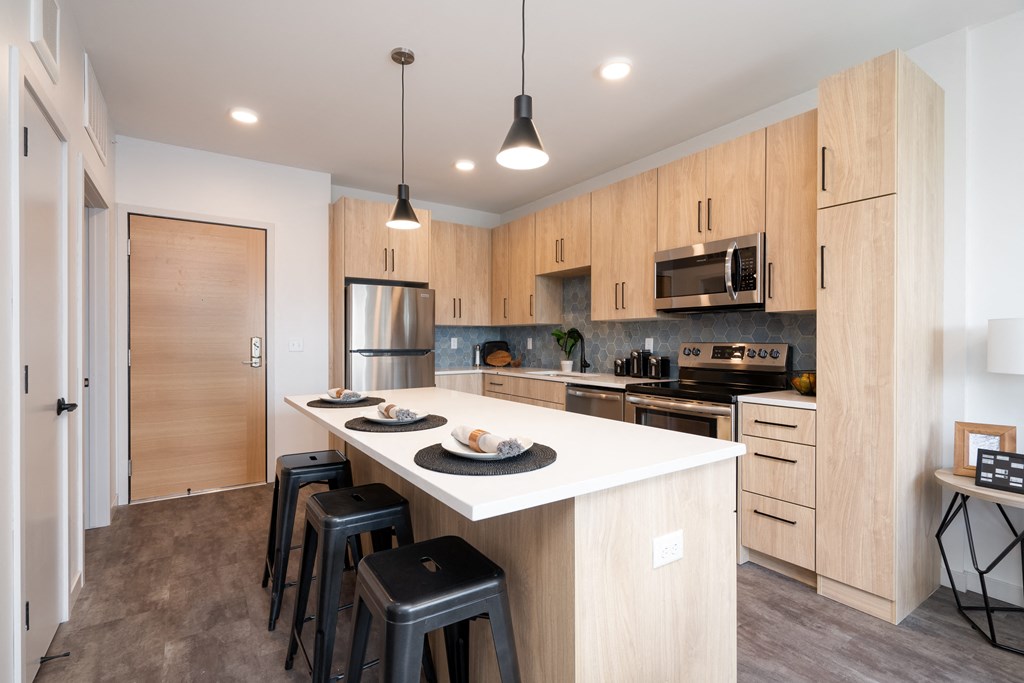 a kitchen with a large island with a white counter top and black stools