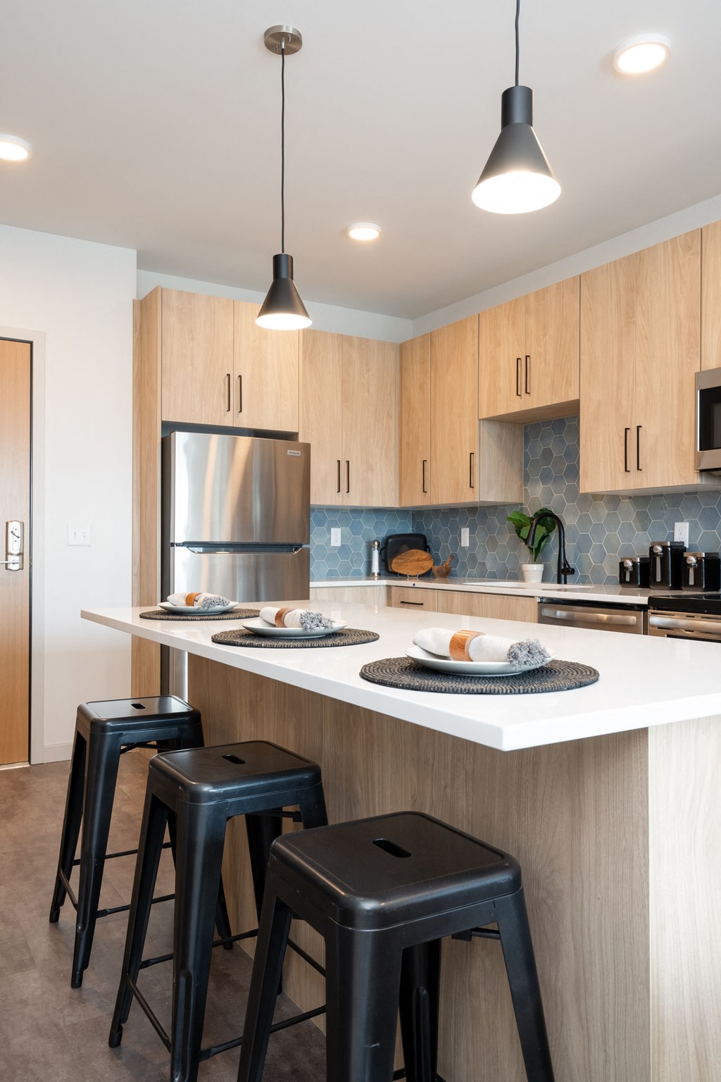 a kitchen with a white counter top and three stools
