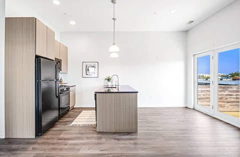 A modern kitchen with a black refrigerator and wooden cabinets.