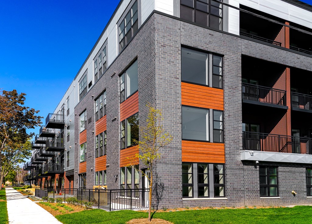 a brick building with orange and gray facade and a sidewalk