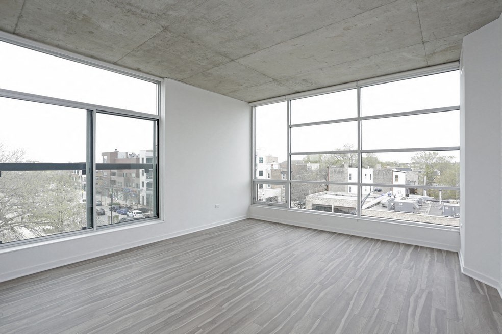 an empty living room with large windows and wood floors