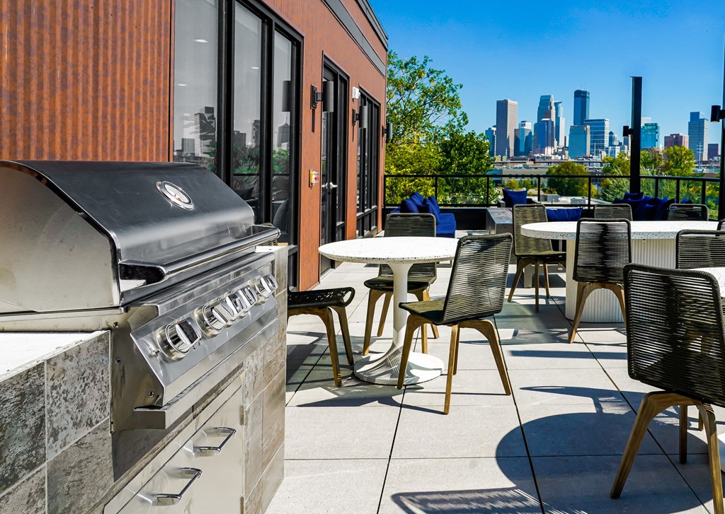 a grill on the patio of a building with tables and chairs