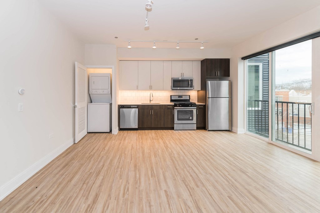 a living room with a wooden floor and a kitchen with stainless steel appliances