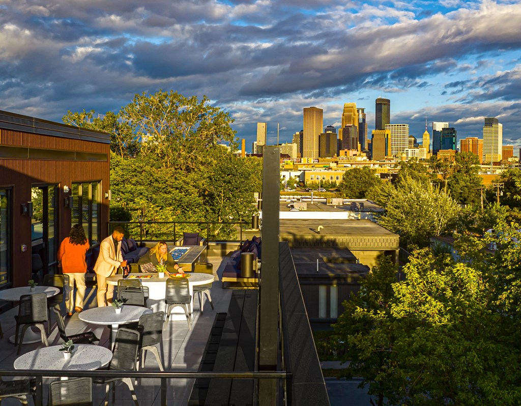 a view of the city skyline from a rooftop patio with tables and chairs