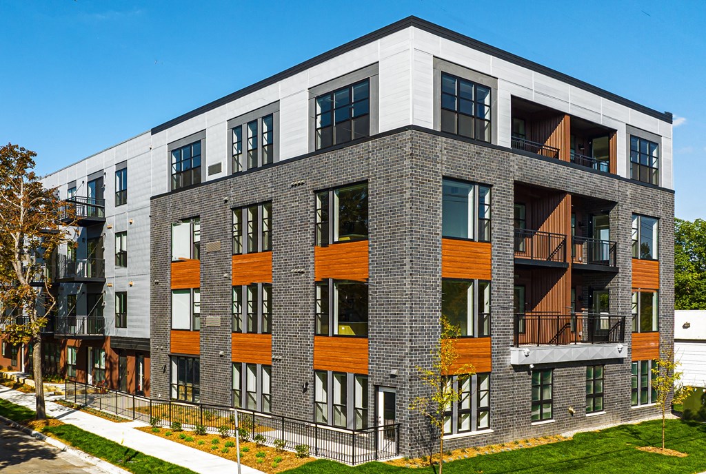 a brick apartment building with windows and a sidewalk