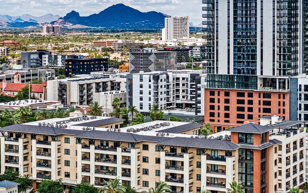 A cityscape with buildings of various designs and a mountain in the background.