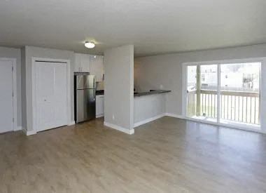 an empty living room and kitchen with a wood floor
