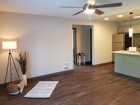 an empty living room with a ceiling fan and a kitchen