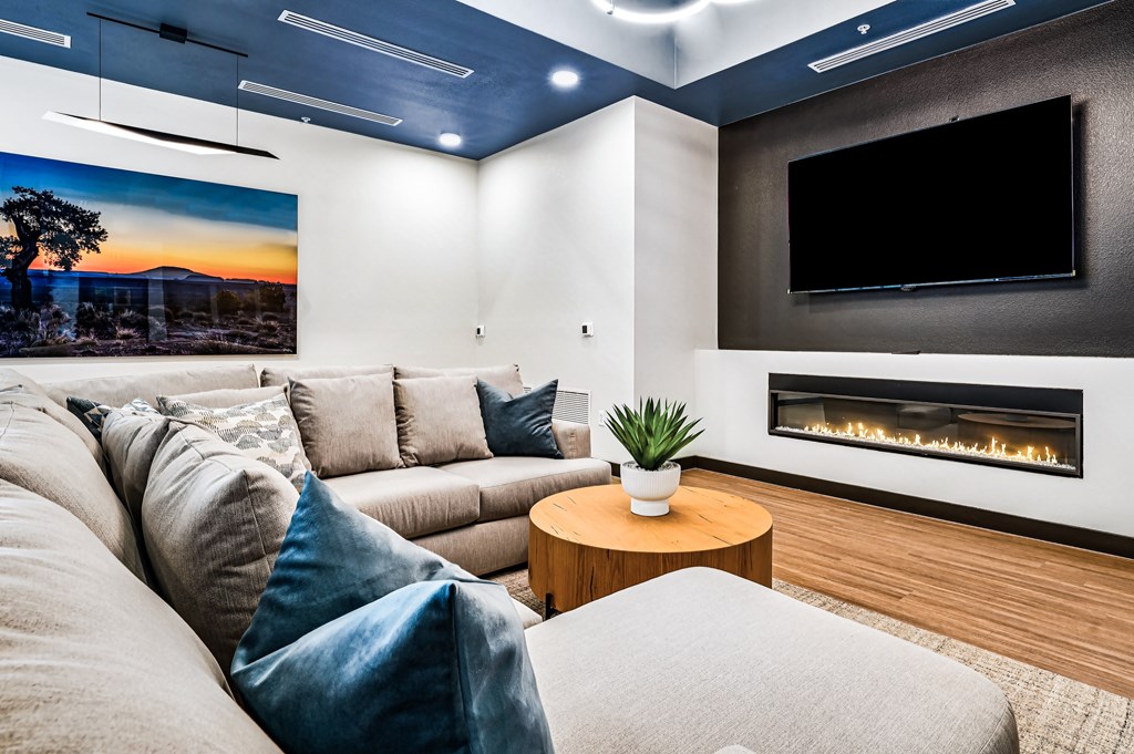 A modern living room with a grey couch, a wooden coffee table, and a fireplace.