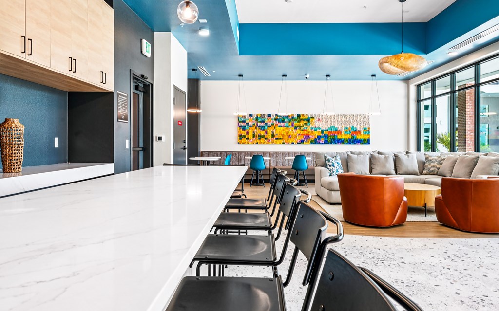A long white table with black chairs is in the foreground of a room with blue walls.