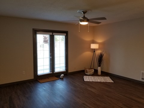 an empty living room with a ceiling fan and a window