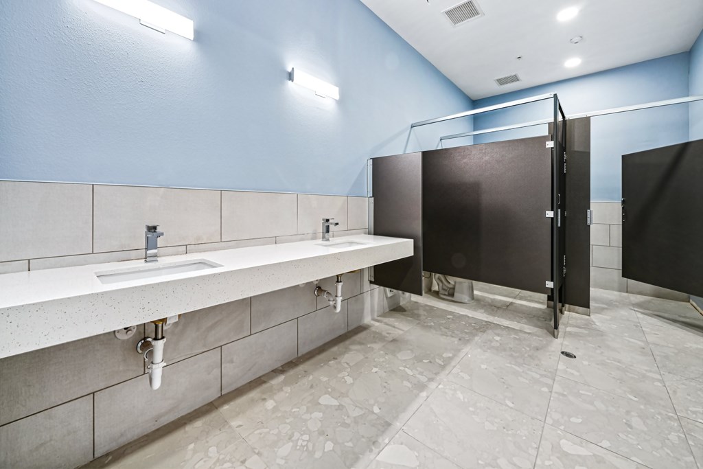 A public restroom with a row of sinks and a row of stalls.