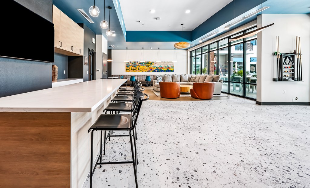 A modern kitchen with a long bar and chairs.