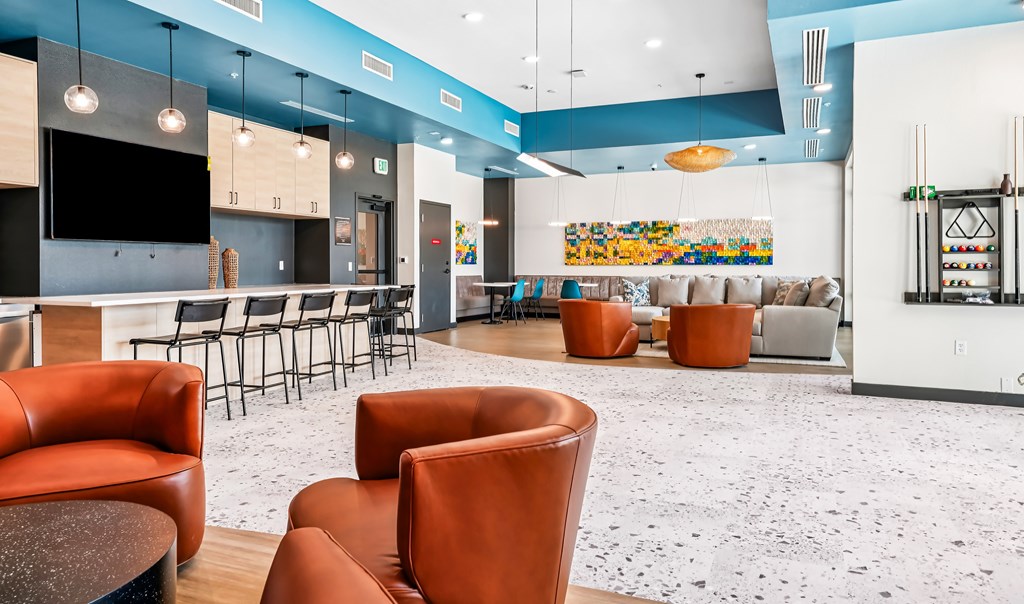 A modern lounge area with orange chairs and a white and blue color scheme.
