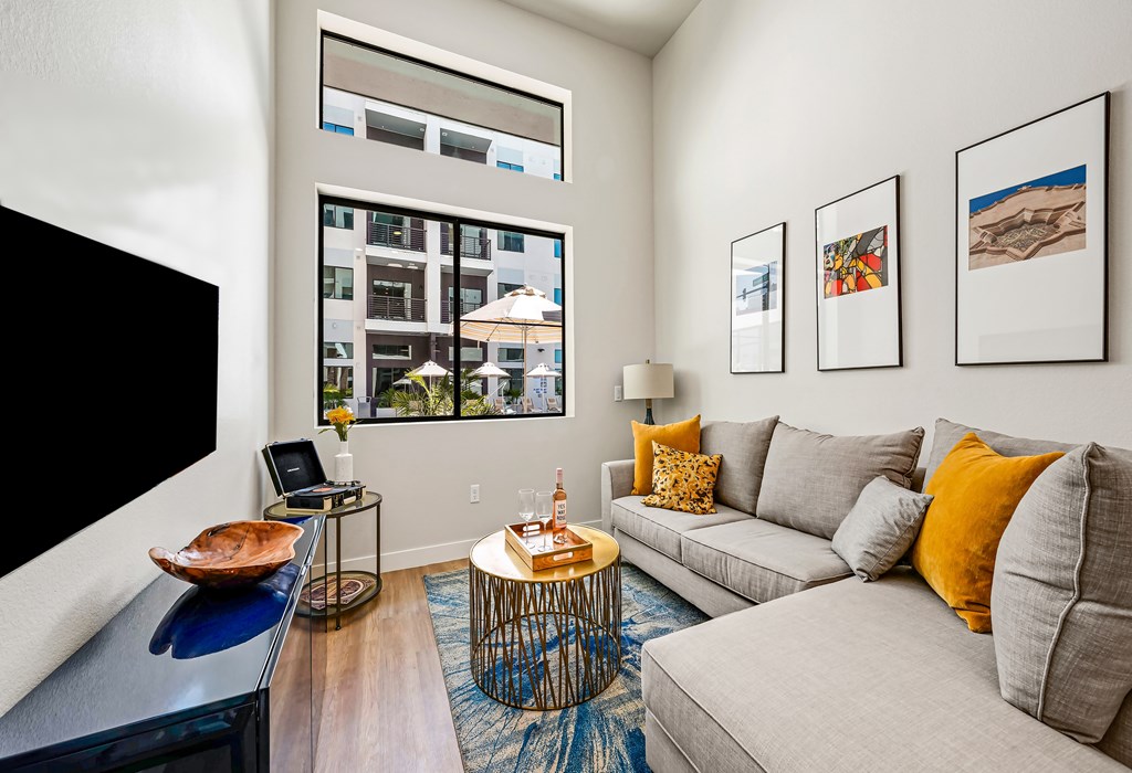 A living room with a grey couch, a coffee table, and a large window.