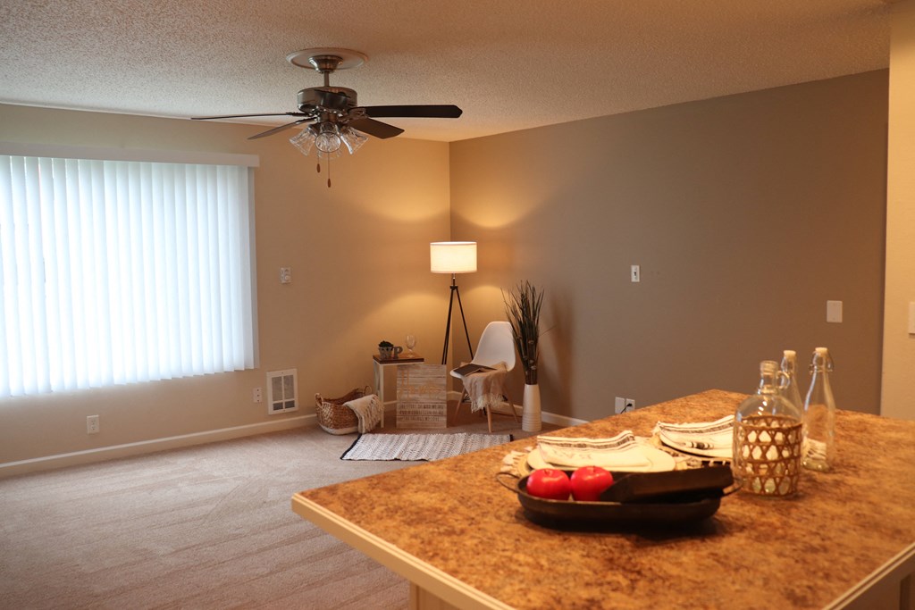 an empty living room with a dining room table and a ceiling fan