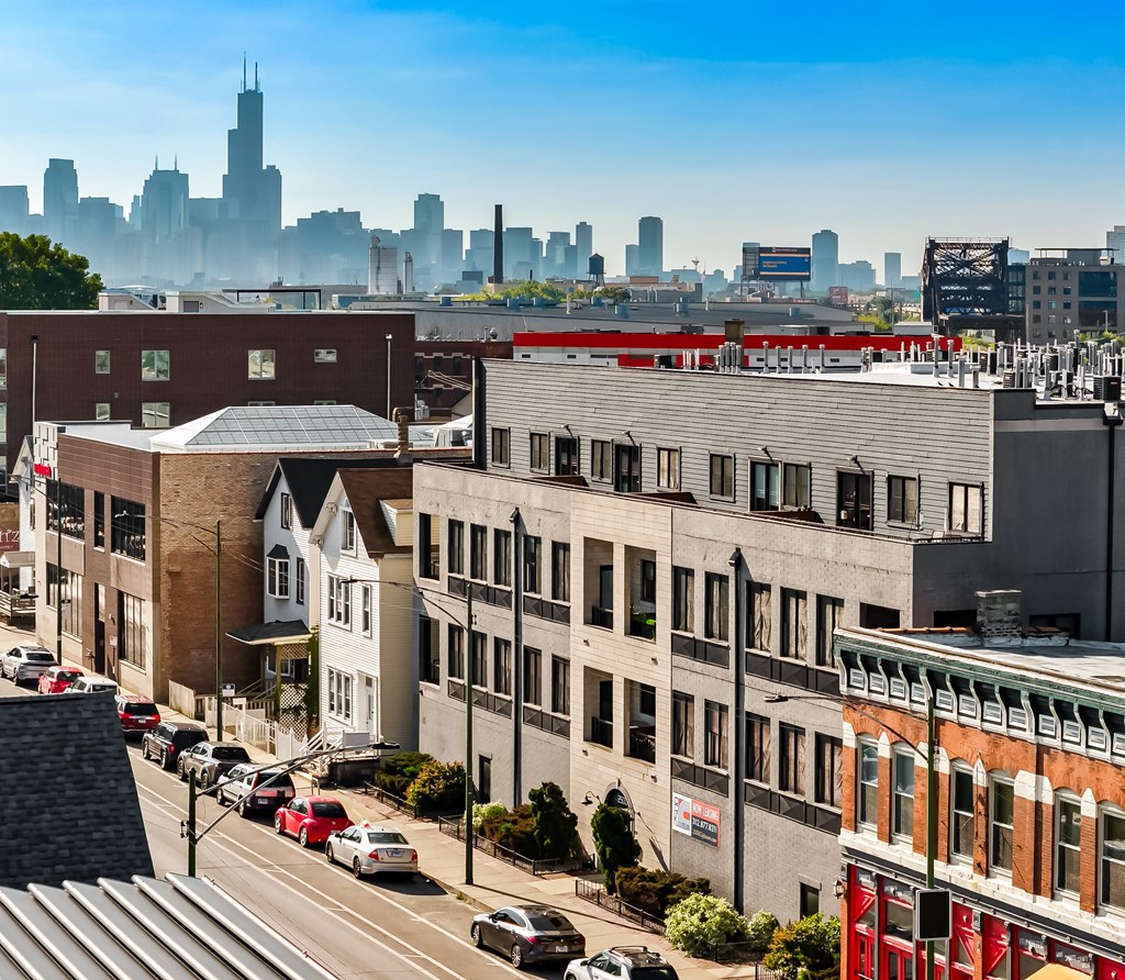 A city street with cars and buildings in the foreground with a city skyline in the background.