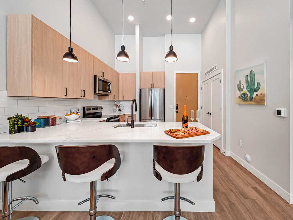 A kitchen with a white counter top and brown chairs.