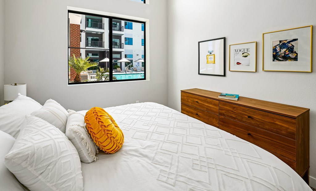 A bedroom with a bed, pillows, a nightstand, and pictures on the wall.
