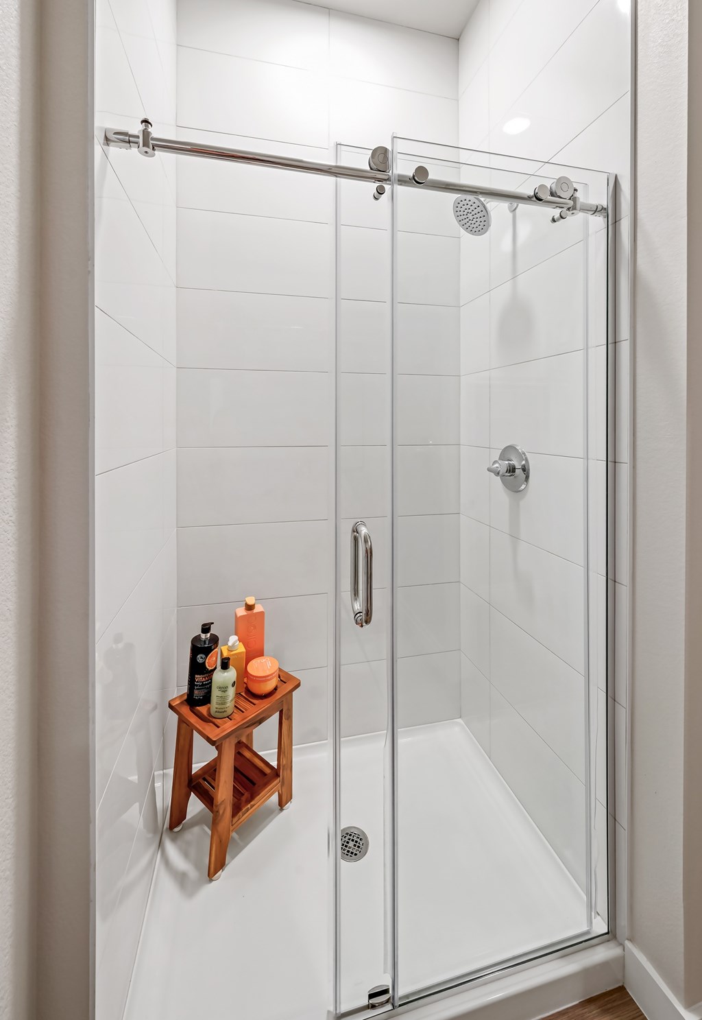 A shower with a shelf and a glass door.
