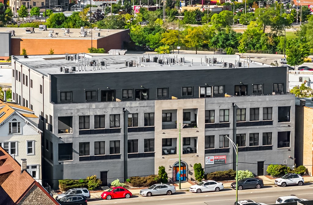 A grey building with a red car parked in front.