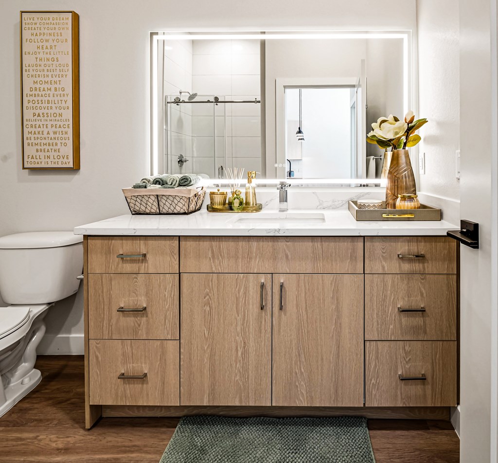A bathroom with a wooden vanity and a mirror above it.