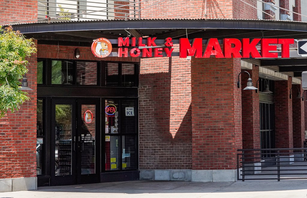 The entrance to a Milk & Honey Market with a red brick wall.