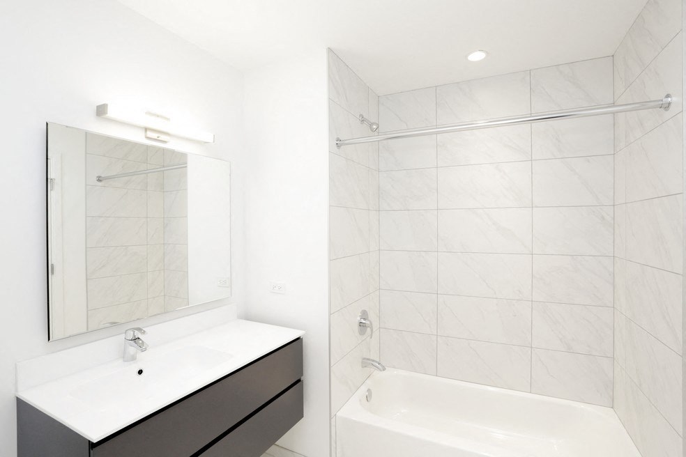 a white bathroom with a tub and a sink and a mirror