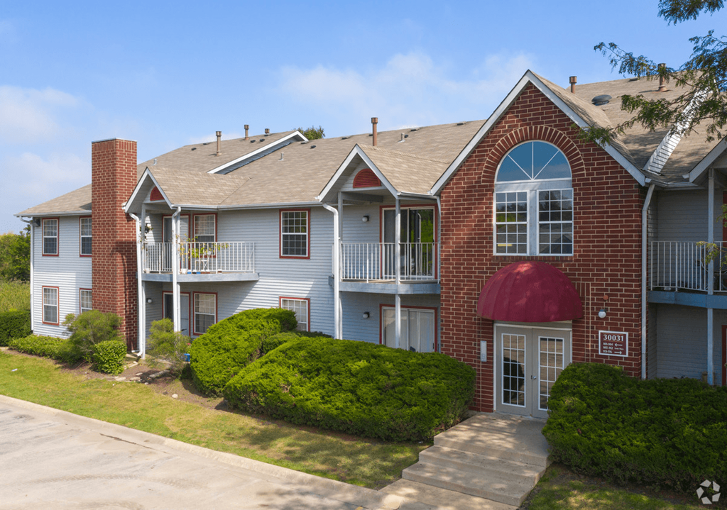 an apartment building with a red roof and white siding