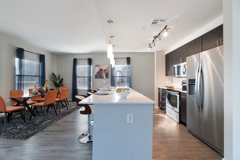 a kitchen and dining room with stainless steel appliances and a white counter top