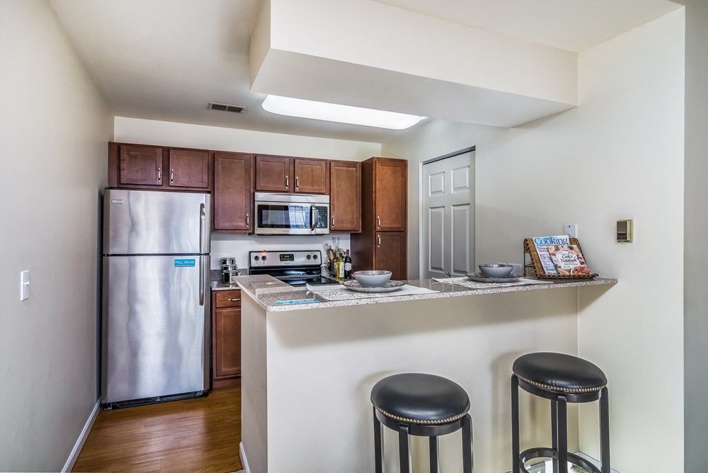 a kitchen with stainless steel appliances and a bar with three stools