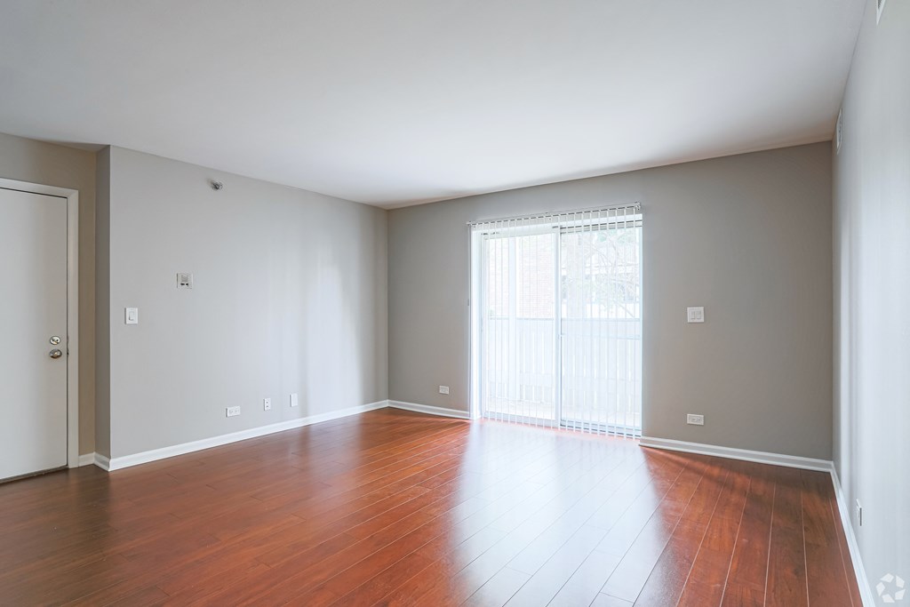 an empty living room with wood floors and a sliding glass door