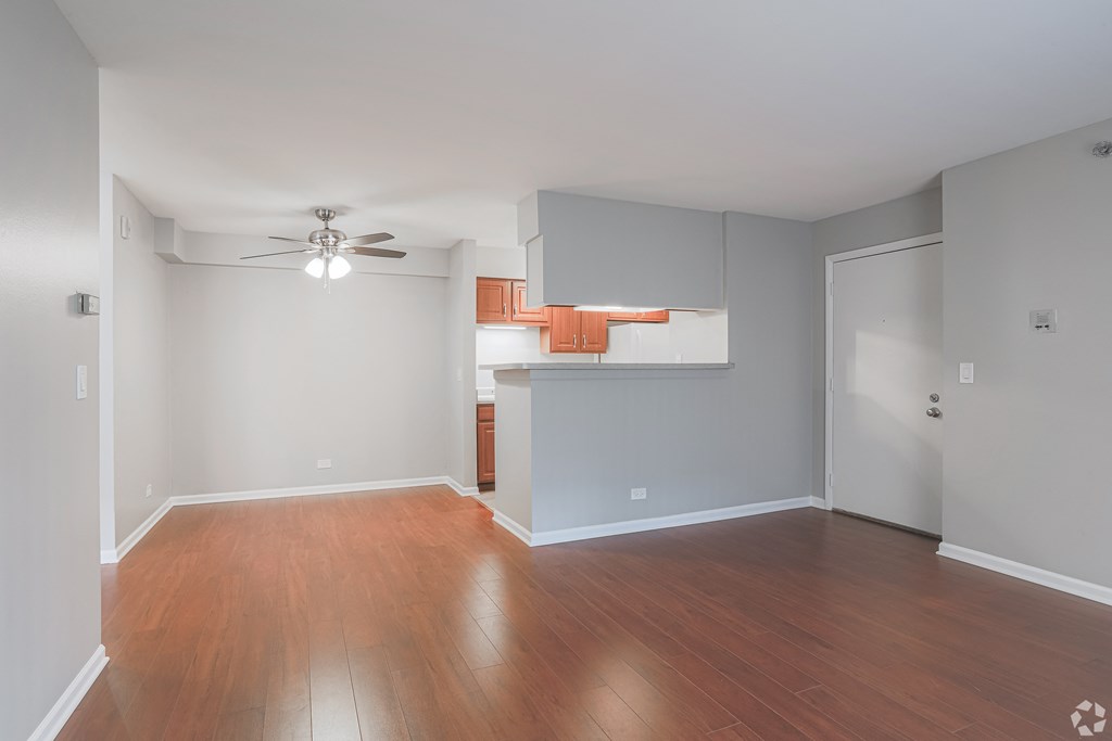 an empty living room with wood flooring and a ceiling fan